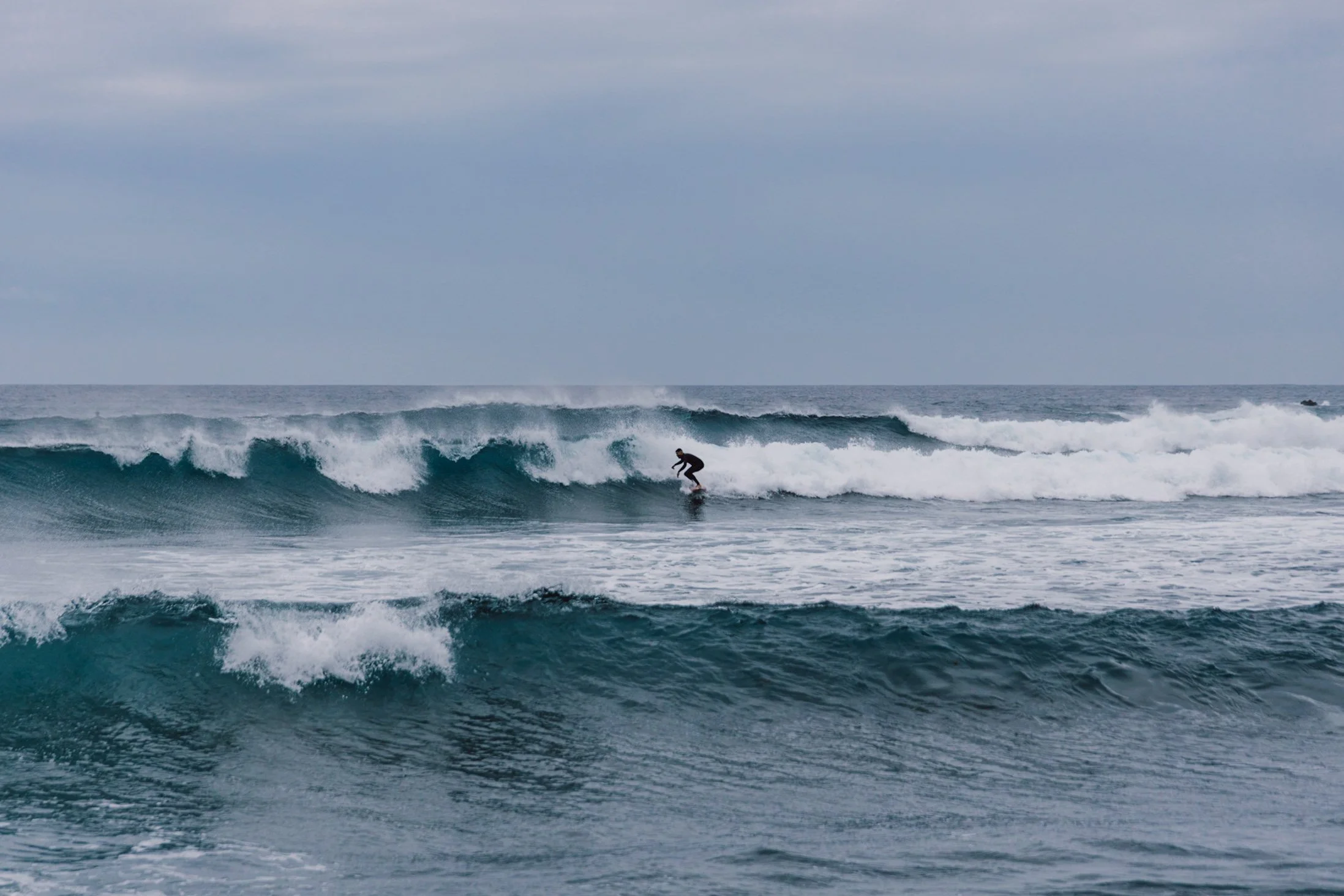 Surfer at Famara beach with Risco cliffs in background, Lanzarote