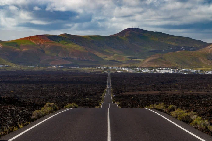 Corredores atravesando los viñedos de La Geria en Lanzarote con volcanes de fondo